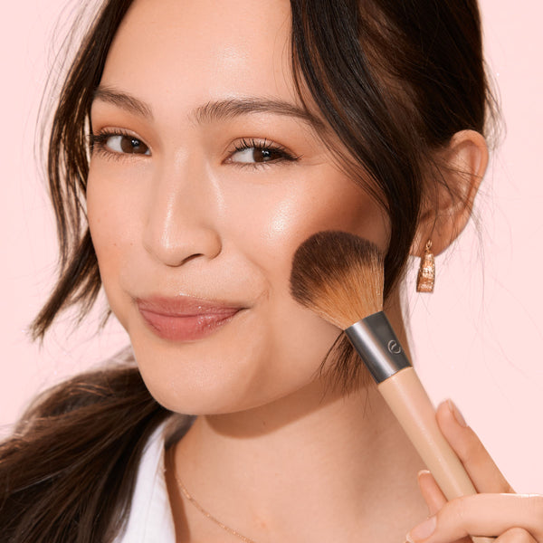 Makeup brush with beige handle and silver ferrule, rounded brown bristles blending makeup