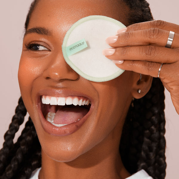 Hand holding a round reusable cotton pad on face during cleansing