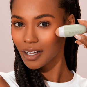 Oil-absorbing facial roller in use on skin, mint-green body with white cap