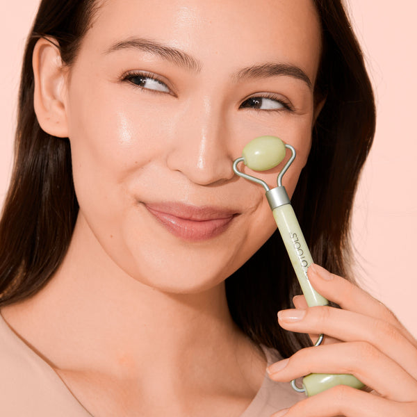 Jade facial roller against a woman’s cheek