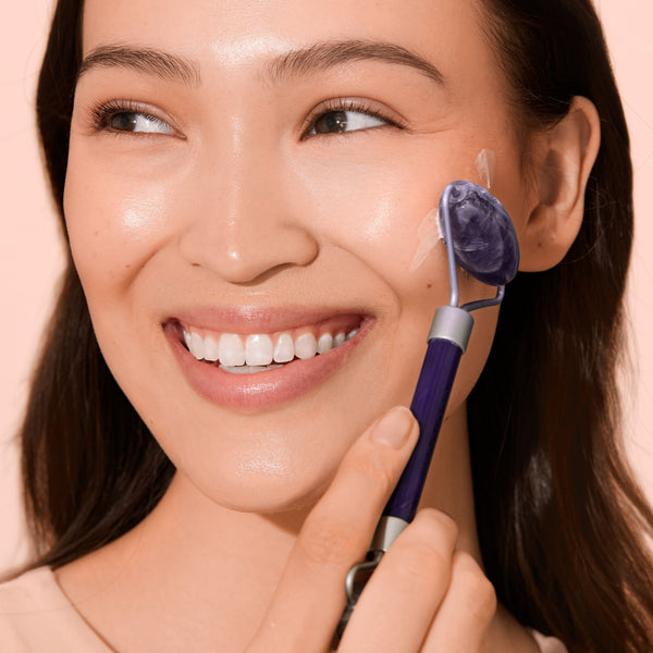 Amethyst facial roller applied to cheek with purple stone head