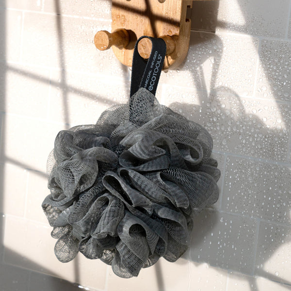Charcoal bath sponge pouf made of dark gray mesh with a hanging loop