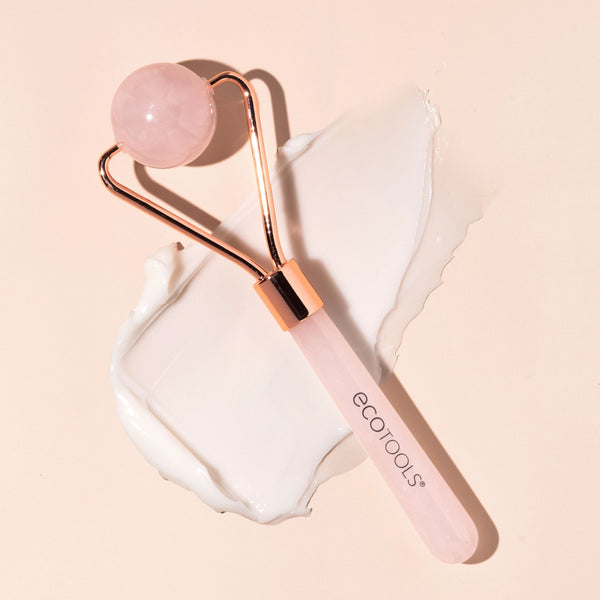 Rose quartz facial roller with round pink stone head and pink handle, rose-gold metal frame