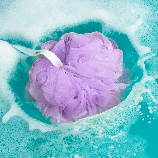 Purple EcoPouf mesh pouf floating in bathwater with bubbles