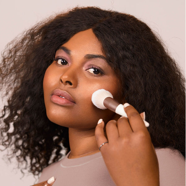 Plush powder brush used to apply powder to cheek, soft white bristles