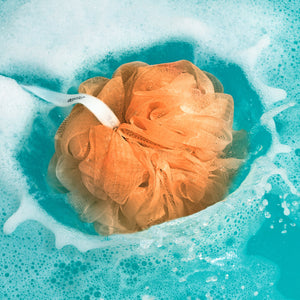Peach EcoPouf scrub pouch in water with bubbles and foam
