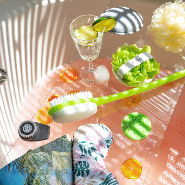 Green bath brush with white oval scrubbing head shown for bathing use