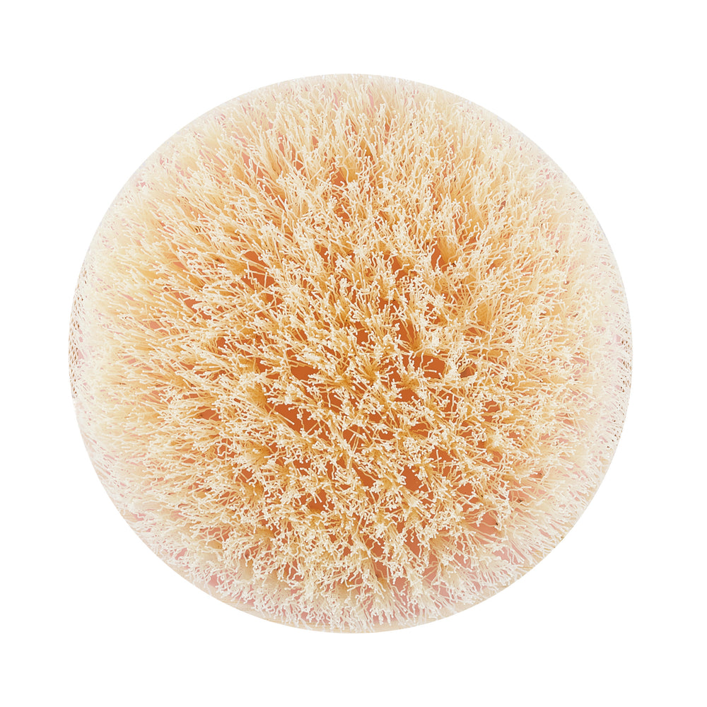 Dry body brush with circular light pink bristle pad and soft-textured fibers
