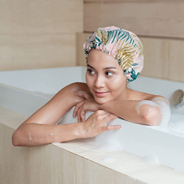 Woman wearing a pastel tropical leaf shower cap with gathered elastic edge in bath