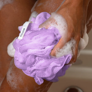 Purple EcoPouf mesh pouf held in a hand, white loop visible