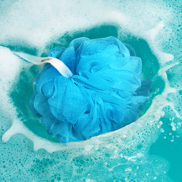 Blue EcoPouf soaking in water with bubbles, rosette sponge texture