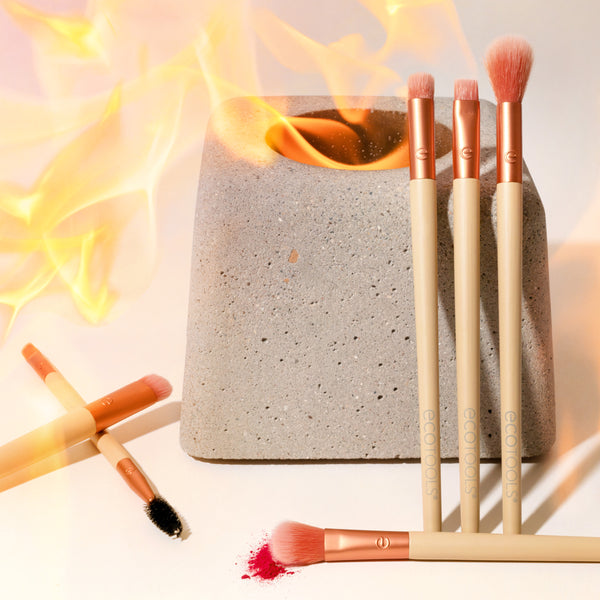 Peach-tipped eye makeup brushes on a beige sponge block with one spare spoolie wand