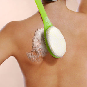 Green-handled bath brush with white oval scrub pad for buffing skin