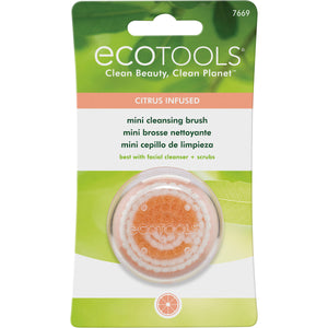 Mini cleansing brush in retail blister pack, shown with an orange scrub dome